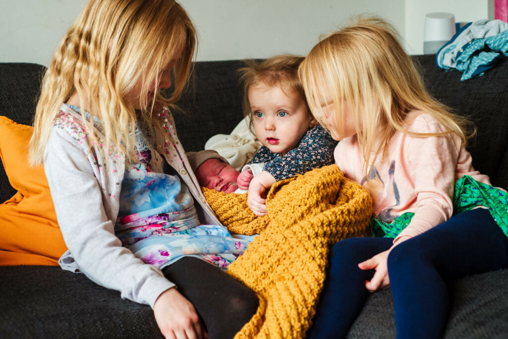 Newborn foto met de zusjes en haar gele dekentje